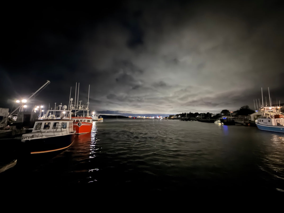 Fishing boats in a quiet Nova Scotia harbour beneath an evening sky, reflecting a moment of pause and reset.