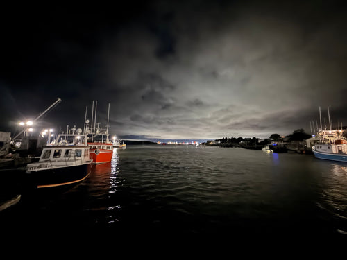 Fishing boats in a quiet Nova Scotia harbour beneath an evening sky, reflecting a moment of pause and reset.